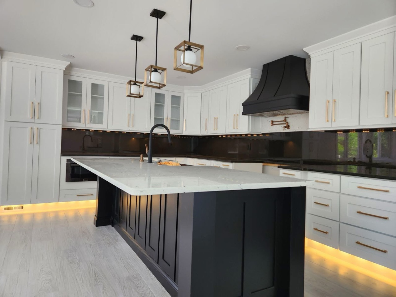 Completed DHR kitchen with white cabinetry, a black island, and brass hardware